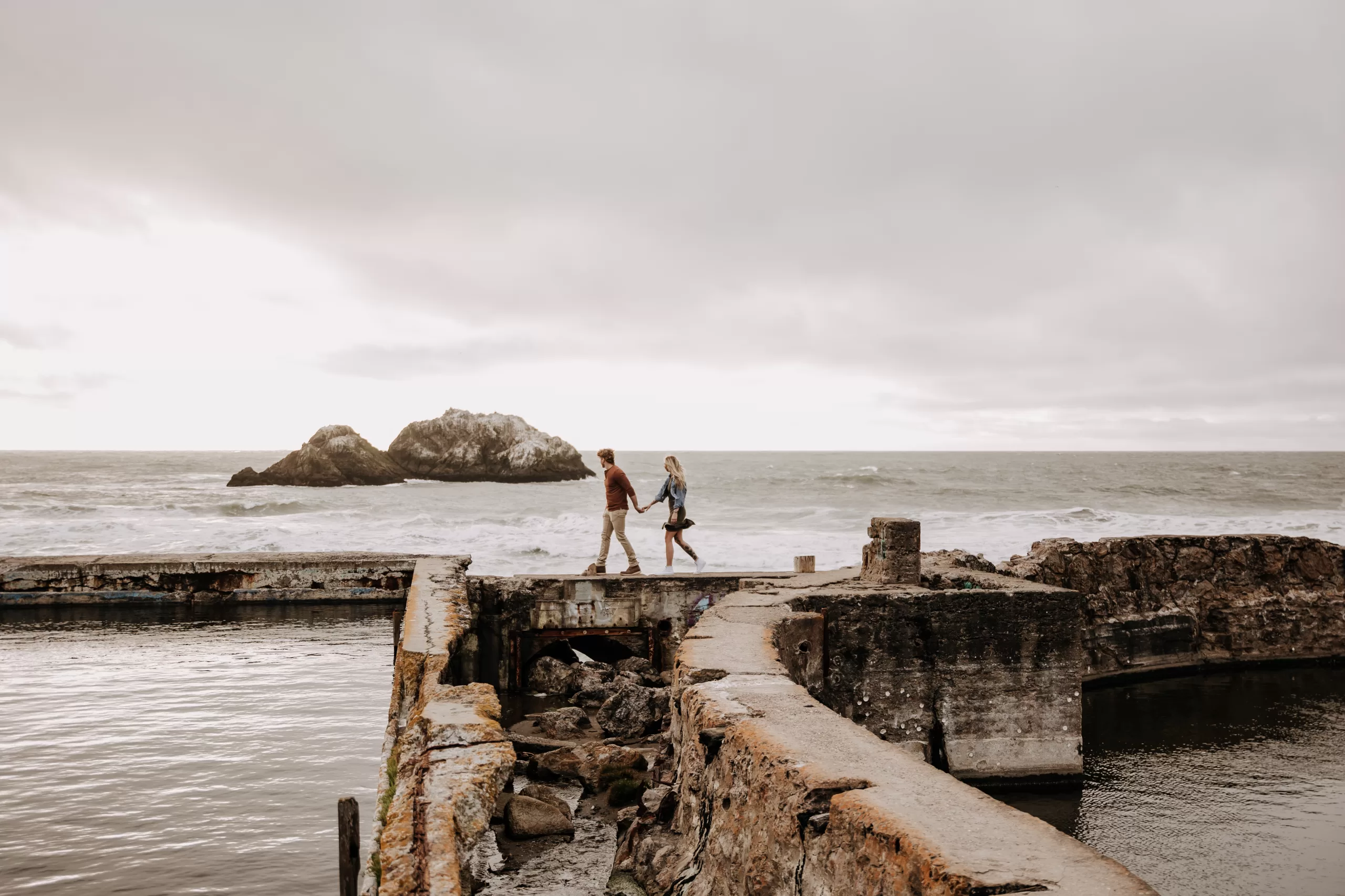 couple walking along the rocks at sutro baths in san francisco